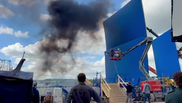 Blue AirPanel raised on a telehandler beside a set during a smoke effect